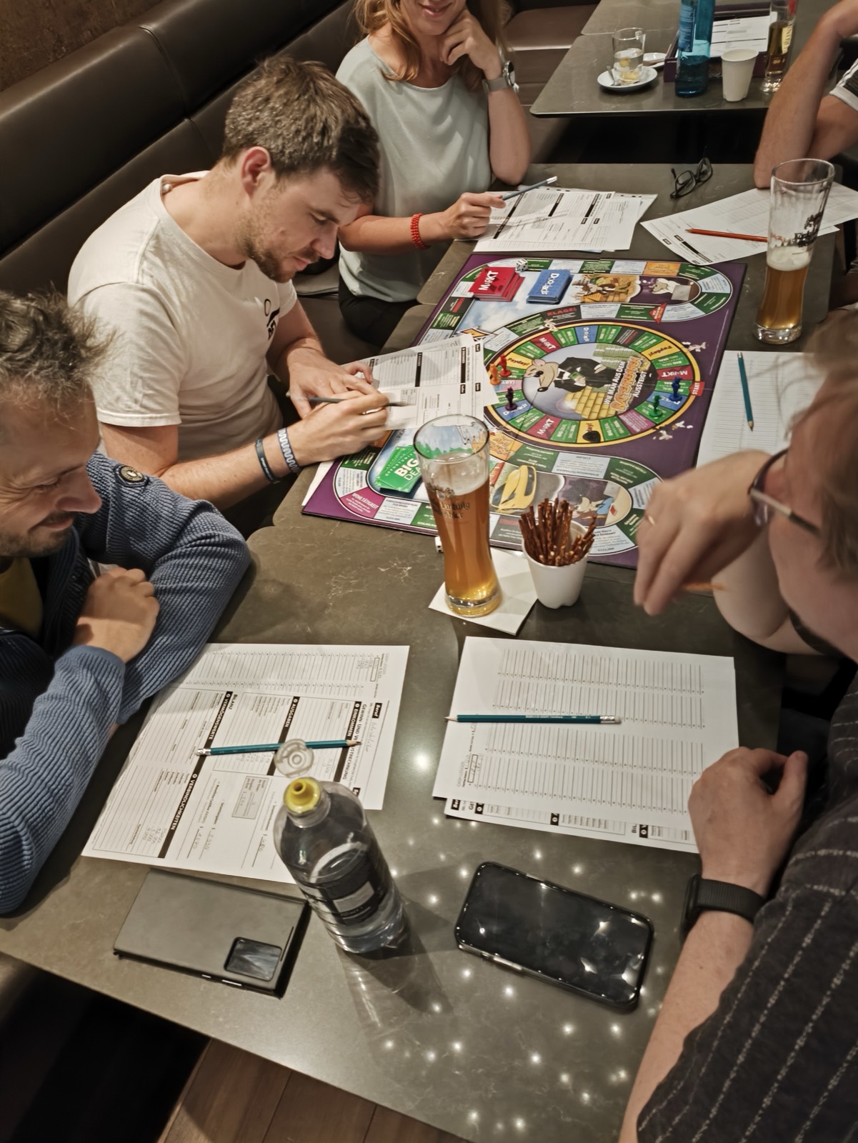 Runde am Tisch beim Cashflow-Spiel, das Spielbrett in der Mitte
